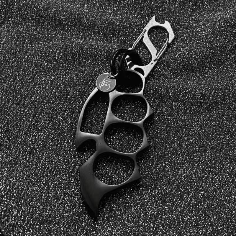 Black keychain EDC knuckle accessory on textured background